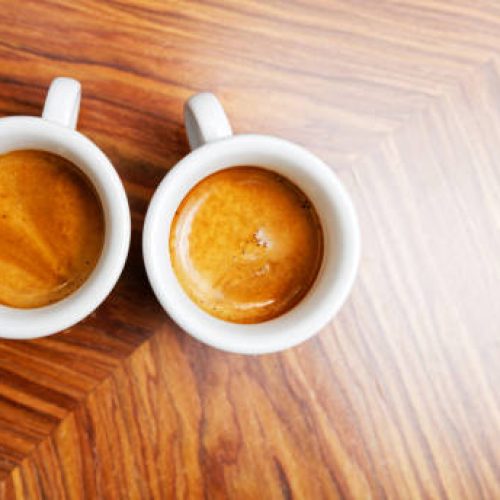 Two white cups of espresso coffee on a wooden table. Top view. Copyspace. Two white cups of espresso coffee on a wooden table. Top view. Copyspace.